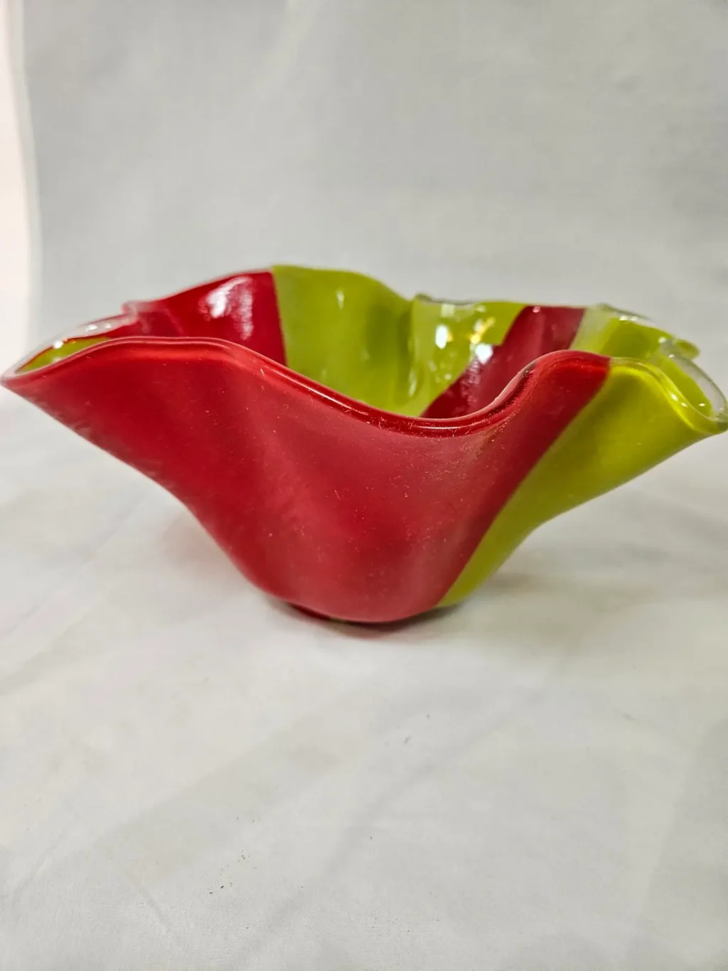 A glass bowl with wavy edges in red and green, called Citrus Splash.