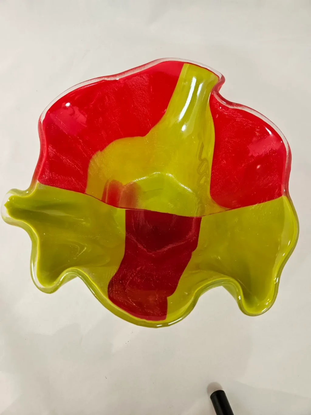 A translucent wavy glass bowl named Citrus Splash, featuring red and yellow sections.