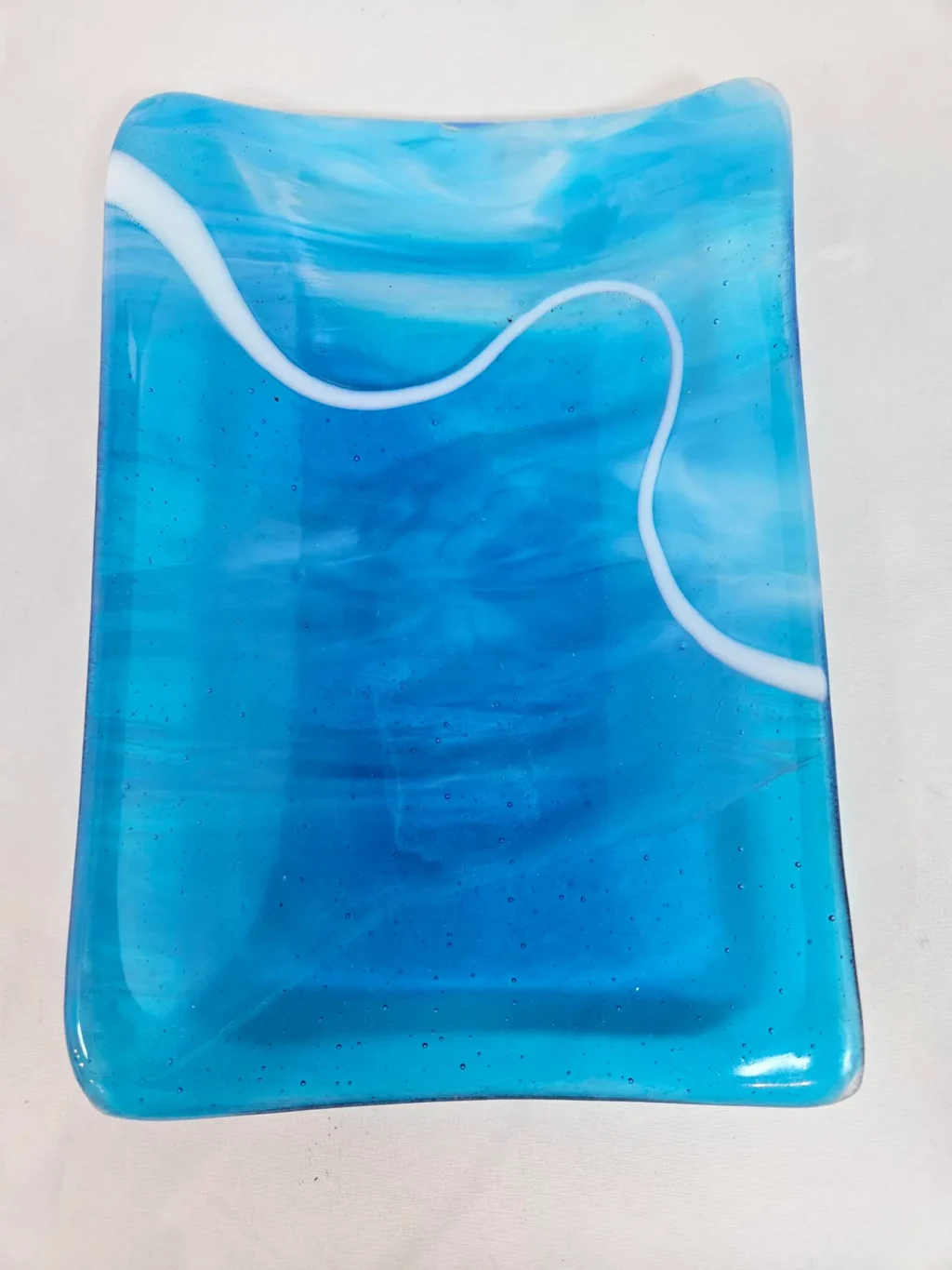 Tranquil Drift is a rectangular blue glass plate featuring a swirling white line design.