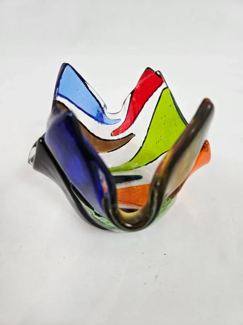 The Prism Flame is a multicolored abstract glass sculpture featuring wavy, folded edges in vibrant shades of blue, red, green, and orange.
