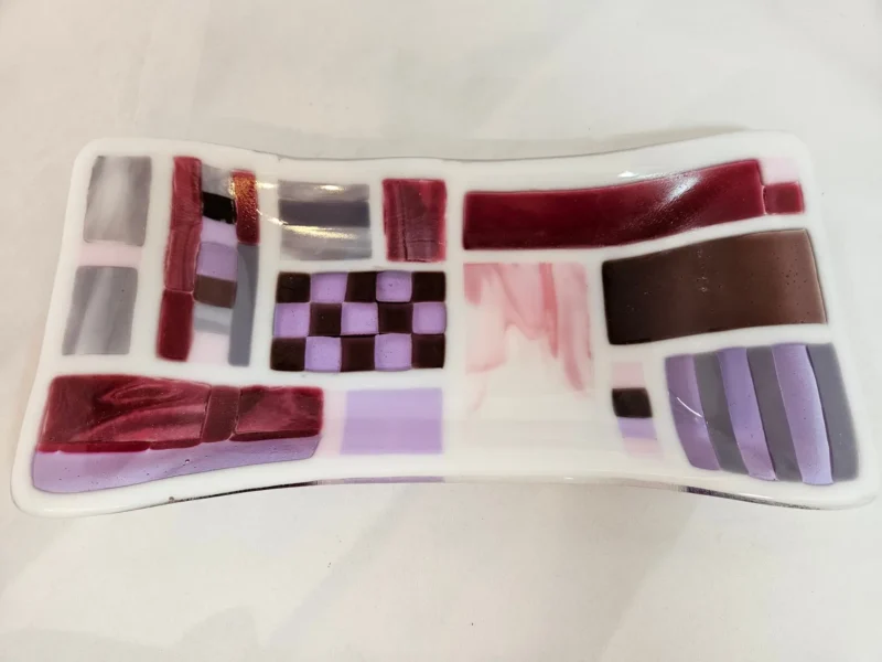 The Burgundy Brushstrokes is a rectangular glass dish with a modern design featuring red, purple, pink, and brown geometric patterns.